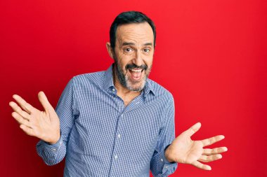 Orta yaşlı İspanyol bir adam, gündelik kıyafetler giyiyor, elleri ve kolları havada, kafası karışmış bir ifade takınıyor. şüphe kavramı. 