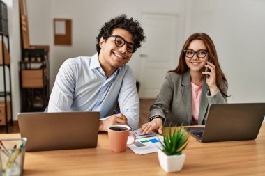 İki iş adamı çalışırken mutlu bir şekilde gülümsüyor ve ofisteki akıllı telefondan konuşuyor..