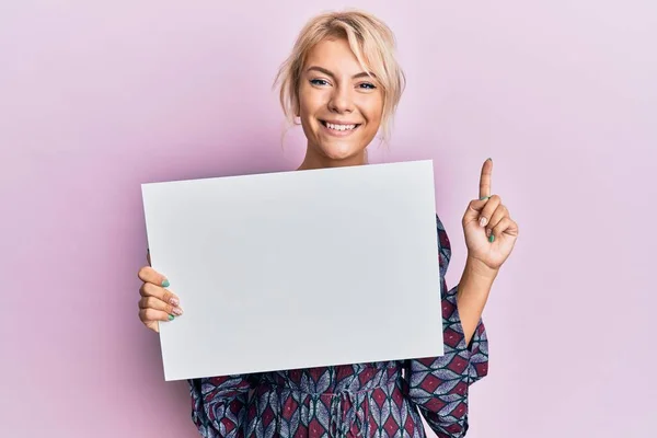 Jovencita Rubia Sosteniendo Banner Vacío Blanco Sonriendo Con Una Idea —  Fotos de Stock
