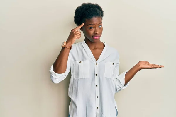 カジュアルな服を着ている若いアフリカ系アメリカ人の少女は コピースペースと額に指を指すことを示すオープン手のひらに混乱し 悩まされています 考えてみてください — ストック写真