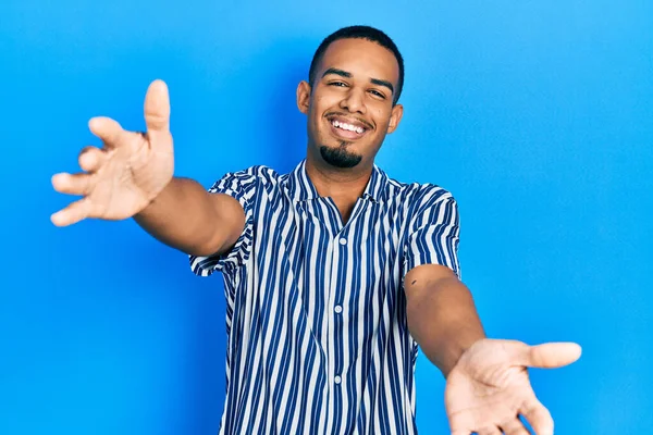Молодий Афроамериканець Одягнений Повсякденний Одяг Дивиться Камеру Усміхаючись Розкритими Обіймами — стокове фото