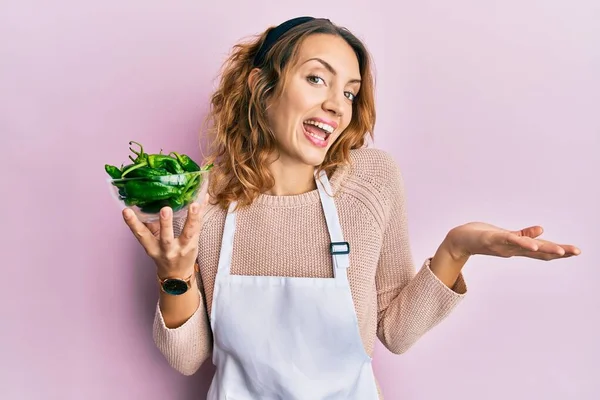 Ung Kaukasisk Kvinna Bär Förkläde Håller Grön Paprika Skål Firar — Stockfoto