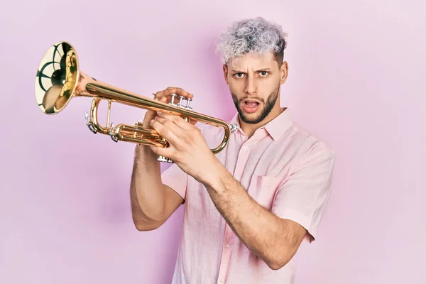 Ung Latinamerikansk Man Med Modernt Färgat Hår Spelar Trumpet Chockansikte — Stockfoto