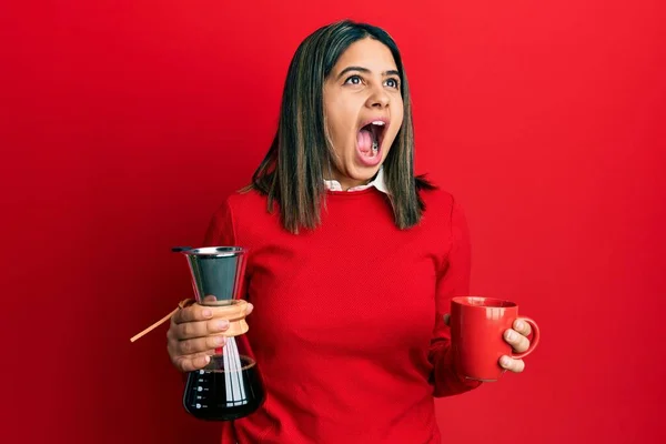年轻的拉丁女人拿着咖啡滤嘴和杯子 怒气冲冲地尖叫着 怒气冲冲地大叫着 抬起头来 — 图库照片