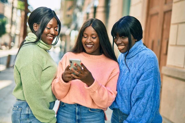 3人のアフリカ系アメリカ人の友人が市内のスマートフォンを使って笑顔で — ストック写真
