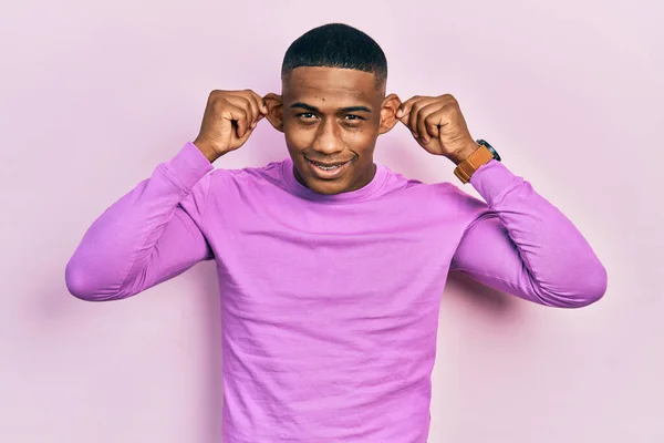 若い黒人男性の指で耳を引く笑顔カジュアルなピンクのセーターを着て 面白いジェスチャー オーディション問題 — ストック写真