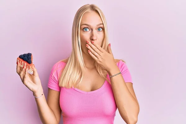 Ung Blond Flicka Håller Cheesecake Skiva Täcker Munnen Med Handen — Stockfoto