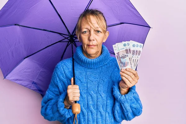 傘を差した中世のブロンドの女性とロシアのルーブル紙幣が顔に深刻な表情でリラックスしました カメラを見ているだけで — ストック写真