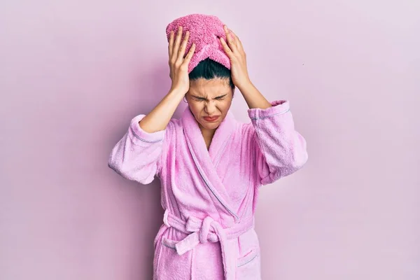 痛みや片頭痛のために絶望的な頭痛やストレスに苦しんでシャワータオルキャップやバスローブを身に着けている若いヒスパニック系の女性 手を頭に — ストック写真