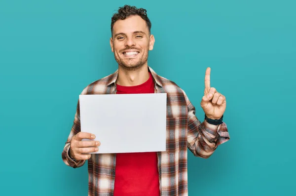 Young Hispanic Man Holding Blank Empty Banner Surprised Idea Question — Stock Photo, Image