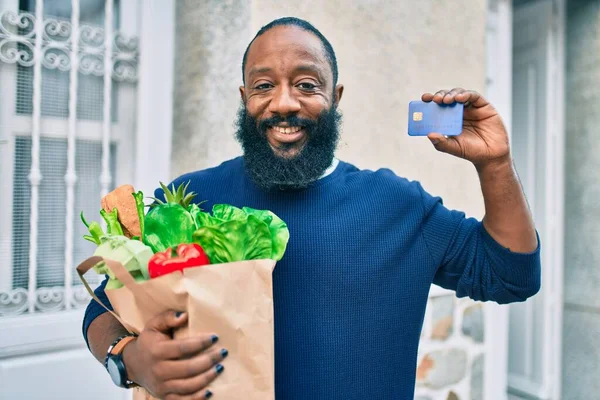 Hombre Afroamericano Con Barba Sosteniendo Bolsa Papel Supermercado Mostrando Tarjeta —  Fotos de Stock