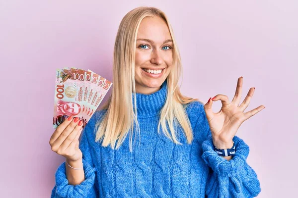 Mladá Blondýnka Drží 100 Dolarů Novozélandských Bankovek Dělá Znamení Prsty — Stock fotografie