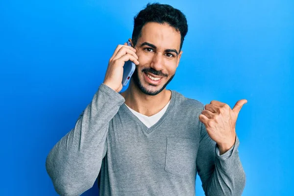 Jovem Hispânico Homem Ter Conversa Falando Smartphone Apontando Polegar Até — Fotografia de Stock