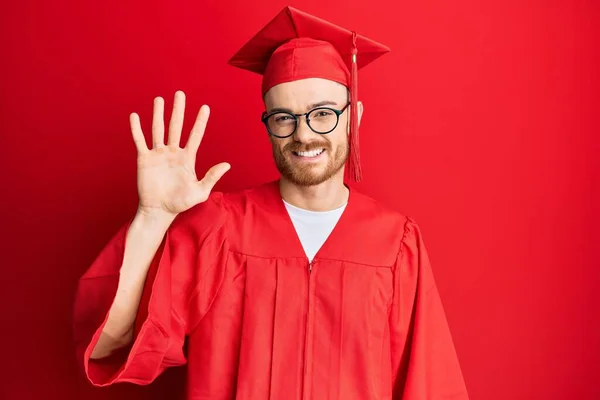 Jovem Ruivo Vestindo Chapéu Formatura Vermelho Roupão Cerimônia Mostrando Apontando — Fotografia de Stock