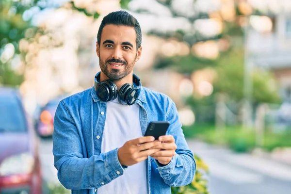 Ung Latinamerikansk Man Ler Glad Med Smartphone Och Hörlurar Stan — Stockfoto