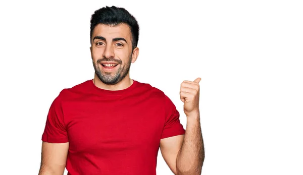 一个留着胡子的西班牙男人 穿着休闲的红色T恤 笑容满面 手指头指向旁边 — 图库照片