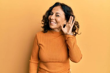 Orta yaşlı İspanyol kadın, günlük giysiler giyip, sırıtarak dedikodu ve dedikoduları dinliyor. Sağırlık kavramı. 