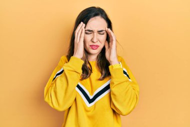 Elleri başının üstünde, günlük kıyafetler giyen genç İspanyol kız, stresten baş ağrısı çekiyor. migren ağrısı. 