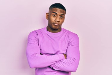 Sıradan pembe kazak giyen, kuşkucu ve gergin genç bir adam. Yüzünde çapraz kollu tasvip etmeyen bir ifade var. negatif kişi. 
