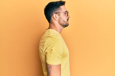 Gündelik kıyafetler ve gözlük takan genç İspanyol adam yan yan yan bakıyor, rahat poz veriyor kendine güvenen bir gülümsemeyle doğal bir yüz ifadesi sergiliyor.. 