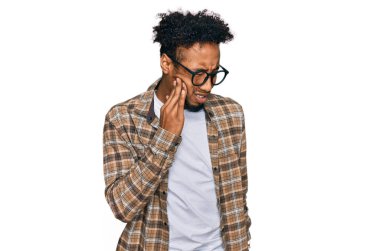 Sakallı ve gözlüklü genç Afro-Amerikan bir adam diş ağrısı ya da diş ağrısı yüzünden ağız ve ellere dokunuyor. dişçi 