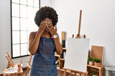Sanat stüdyosunda afro saçlı, yorgun, uykulu ve yorgun bir ifade için gözlerini ovuşturan Afro-Amerikalı genç bir kadın. görme sorunu 