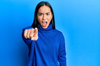 Sıradan bir süveter giyen genç Asyalı kadın kameraya kızgın ve sinirli bir şekilde seni işaret ediyor. 