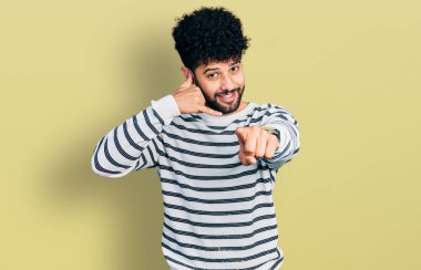 Sakallı, sıradan çizgili süveter giyen, gülümseyen, telefonda konuşan ve seni işaret eden genç bir Arap. Ara beni.. 