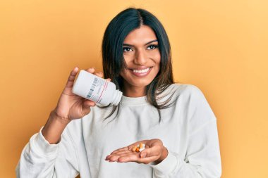 Genç Latin transseksüel kadın elinde haplarla gülümsüyor, yan tarafa bakıyor ve düşünüyor.. 