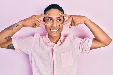 Genç Afrikalı Amerikalı adam zafer işareti yapıyor ve barış jesti gülümsüyor.. 