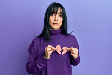 Kırık kalp kağıdı şeklinde kâkülleri olan esmer bir kadın yüzünde ciddi bir ifadeyle rahatlamış. Basit ve doğal bir şekilde kameraya bakıyorsun.. 