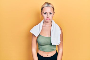 Spor kıyafetleri ve havlu giyen genç sarışın kız üzgün ve endişeli, sinirli ve korkmuş bir şekilde ağlıyor. hüzünlü ifade. 