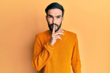 Gündelik kıyafetler giyen genç İspanyol adam parmakları dudaklarında sessiz olmak istiyor. sessizlik ve gizli konsept. 