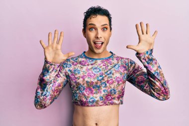 Makyaj giysileri giymiş yakışıklı bir adam on numarayı gösterip işaret ederken kendine güvenen ve mutlu bir şekilde gülümsüyor.. 