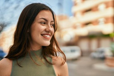 Genç beyaz kız gülümseyerek şehirde mutlu mesut duruyor..