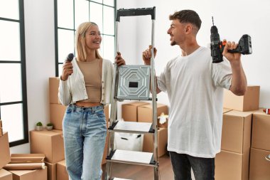 Genç beyaz çift mutlu bir şekilde gülümsüyor işçi merdivenlerini tutuyor ve yeni evlerinde talim yapıyor..