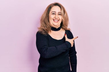 Orta yaşlı, beyaz, günlük kıyafetler giyen, neşeli, yüzünde mutlu ve doğal bir ifadeyle, elleri ve parmaklarıyla yüzünü gösteren bir gülümseme olan bir kadın. 