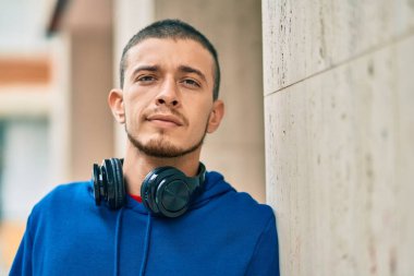 Şehirde kulaklık takarak mutlu gülümseyen genç İspanyol adam.