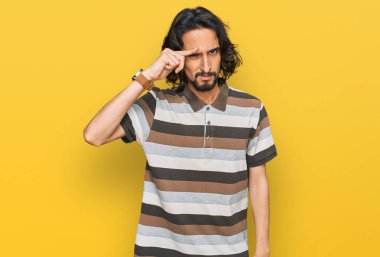 Alnındaki sivilceden mutsuz olduğunu gösteren günlük kıyafetler giyen genç İspanyol adam, siyah başlıklı çirkin enfeksiyon. sivilce ve deri problemi 