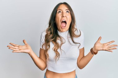 Genç esmer kadın, sıradan beyaz tişörtler giyip deli gibi bağırıyor ve agresif bir ifade ve kollarla bağırıyor. hüsran kavramı. 