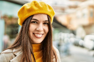 Genç İspanyol kız gülümseyerek şehirde mutlu mesut dikiliyor..