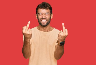 Handsome young man with beard wearing casual tshirt showing middle finger doing fuck you bad expression, provocation and rude attitude. screaming excited 