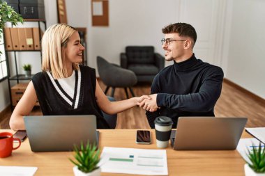 İki iş adamı gülümseyerek ofiste el sıkışırken mutlu olur..