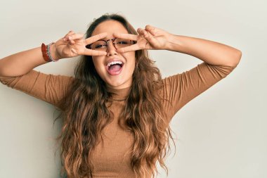 Gündelik kıyafetler giyen ve gözlük takan genç İspanyol kız barış sembolü yapıyor. Yüzünde parmaklar, gülümseyerek zaferi gösteriyor. 