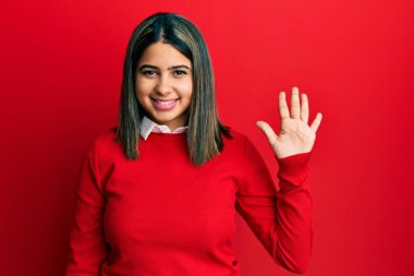 Genç Latin kadın gündelik giysiler giyer ve beş numarayı göstererek gülümserken kendinden emin ve mutluydu.. 