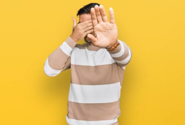 Sakallı, sıradan kıyafetler giyen, gözlüklü, elleriyle gözlerini kapatan, üzgün ve korku dolu hareketler yapan yakışıklı bir adam. utangaç ve olumsuz kavram. 