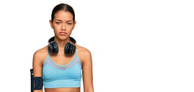 Güzel İspanyol kadın spor giyer ve kulaklık takar. Yüzünde ciddi bir ifade vardır. Basit ve doğal bir şekilde kameraya bakıyorsun.. 