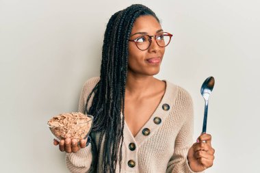 Saçları örgülü, sağlıklı tahıl gevrekleri yiyen Afro-Amerikalı bir kadın gülümseyerek yan tarafa bakıyor ve şöyle düşünüyor:. 