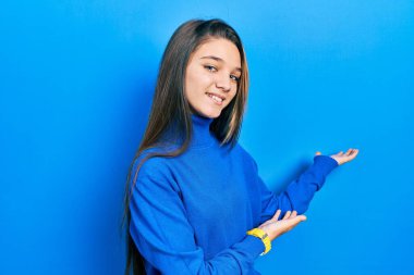 Balıkçı yaka kazak giyen genç esmer kız gülümseyerek doğal bir şekilde içeri girmeye davet ediyor. 