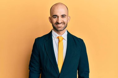 Genç İspanyol bir adam iş elbisesi giyiyor ve yüzünde mutlu ve havalı bir gülümsemeyle kravat takıyor. şanslı kişi. 